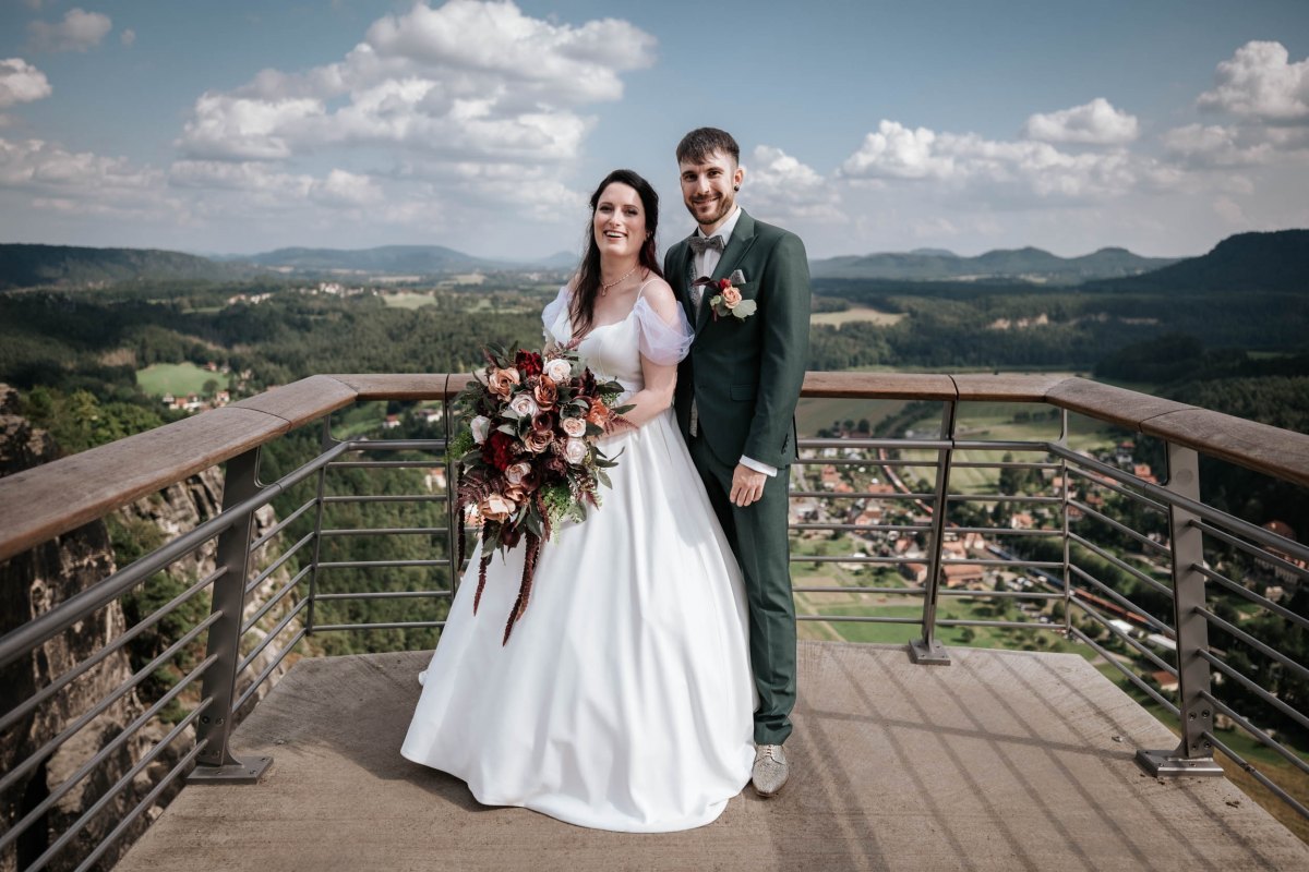 Brautpaar auf einem Aussichtspunkt mit Blick über die Landschaft