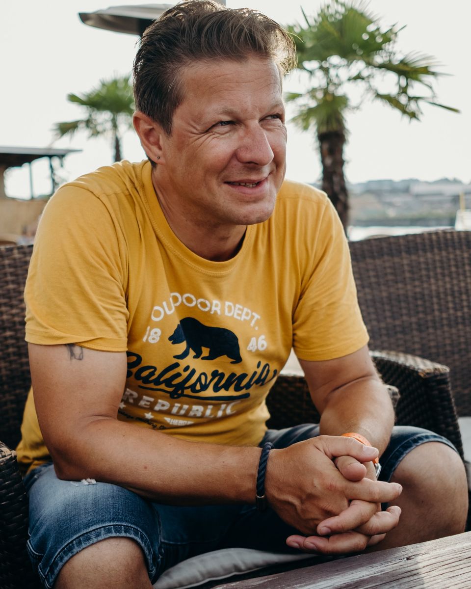 Torsten Kellermann lachend im gelben T-Shirt auf einer Terrasse