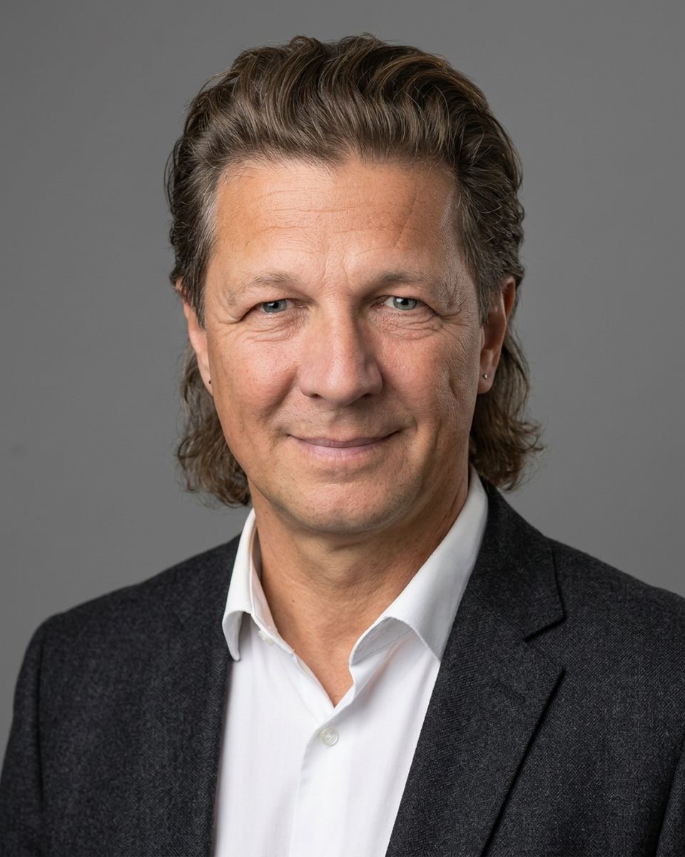 Business-Portrait von Torsten Kellermann im Sakko vor grauem Hintergrund